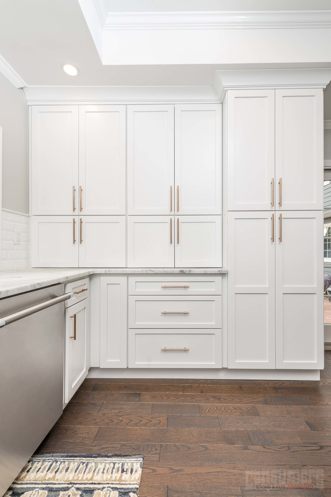Large u-shaped plywood floor eat-in kitchen photo in New York with a farmhouse sink, recessed-panel cabinets, white cabinets, quartzite countertops, white backsplash, ceramic backsplash, stainless steel appliances and an island