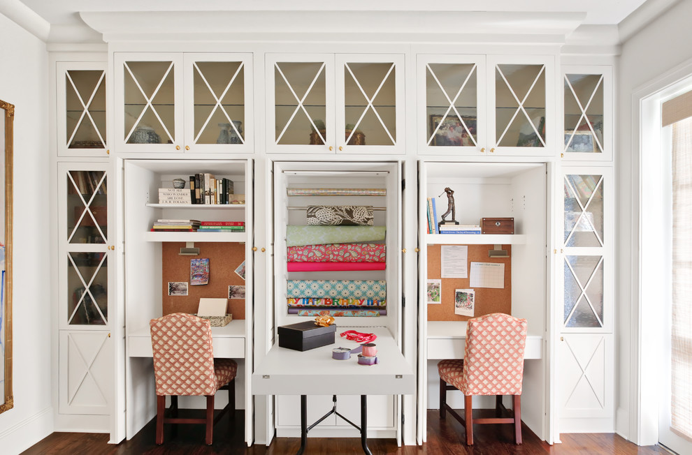 This is an example of a traditional craft room in Nashville with white walls, medium hardwood floors, a built-in desk and brown floor.