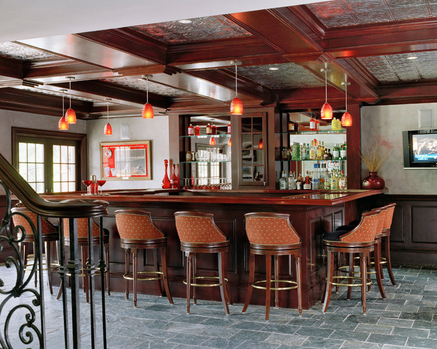 Inspiration for an expansive mediterranean u-shaped seated home bar in Boston with an undermount sink, recessed-panel cabinets, dark wood cabinets, wood benchtops, mirror splashback, slate floors and brown benchtop.