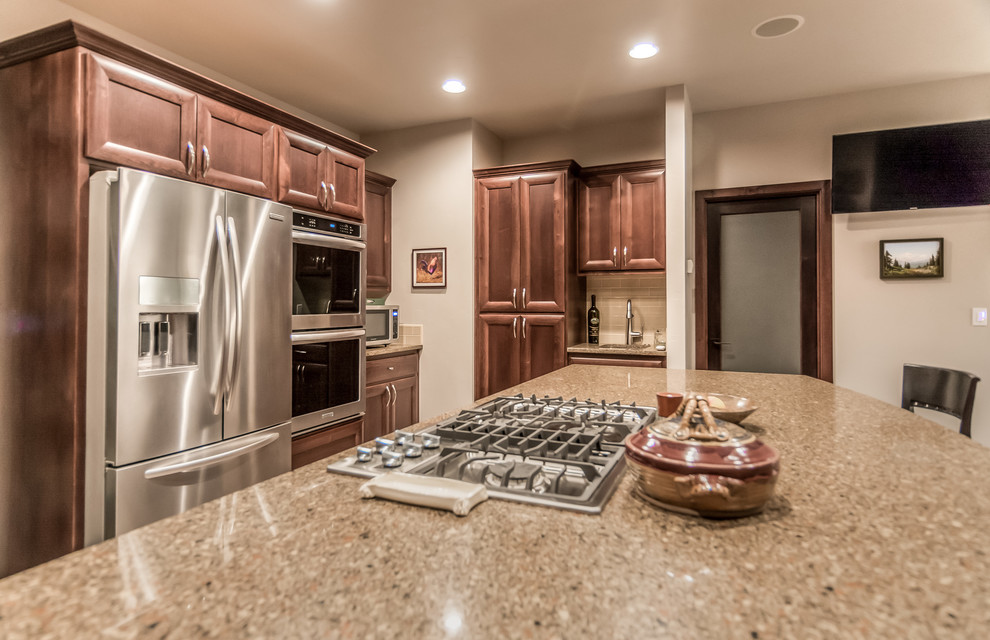 Example of a large mountain style l-shaped porcelain tile open concept kitchen design with an undermount sink, recessed-panel cabinets, dark wood cabinets, granite countertops, beige backsplash, subway tile backsplash, stainless steel appliances and an island
