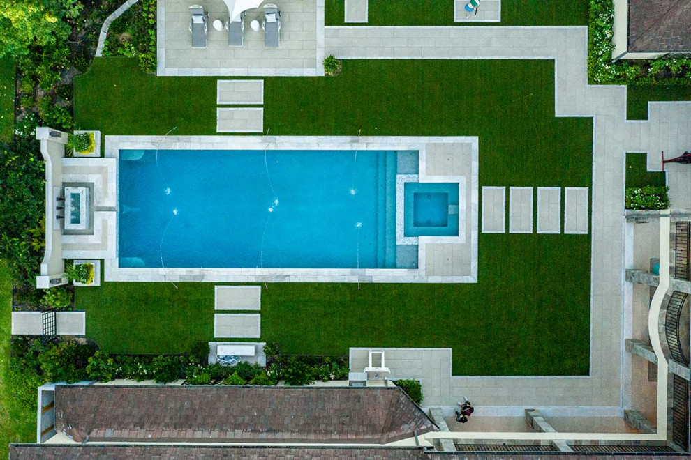 Large backyard rectangular pool in Houston with natural stone pavers.