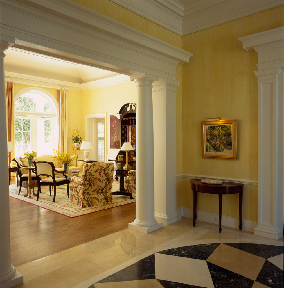 Large traditional foyer in Miami with yellow walls and marble floors.