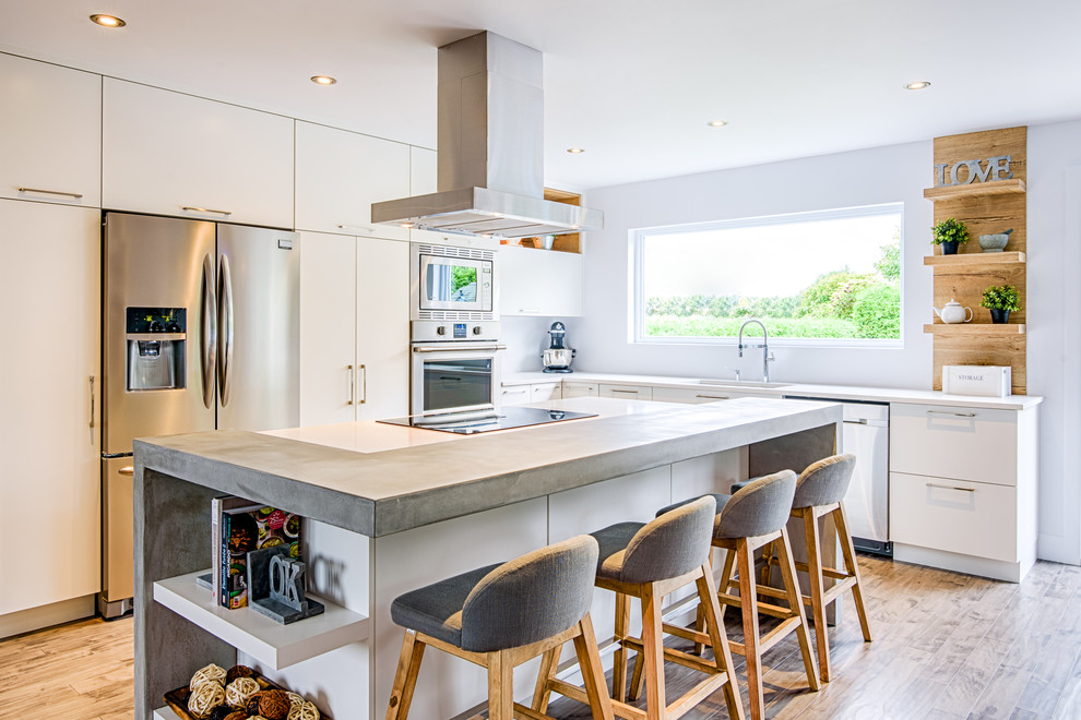 This is an example of a mid-sized modern l-shaped eat-in kitchen in Montreal with an undermount sink, flat-panel cabinets, white cabinets, concrete benchtops, stainless steel appliances, painted wood floors, with island and grey floor.