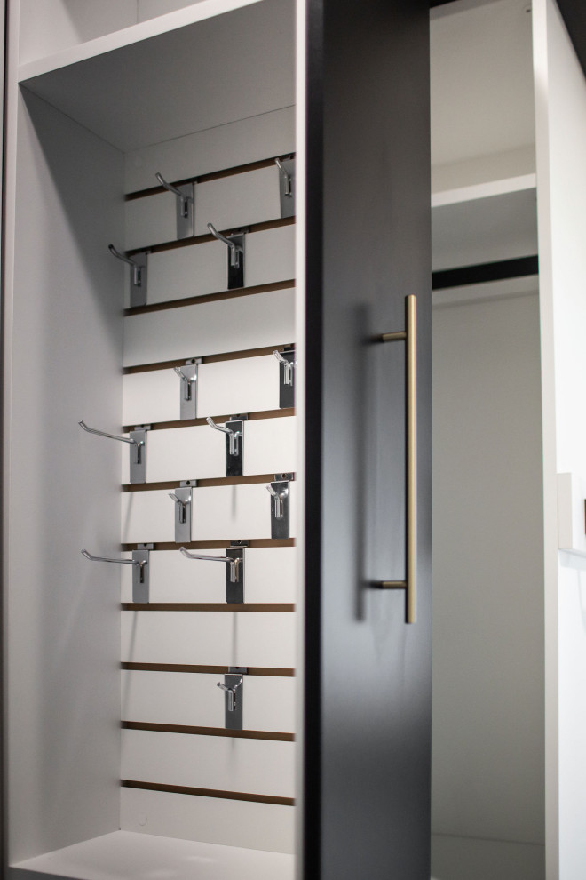 This is an example of a mid-sized transitional gender-neutral walk-in wardrobe in Other with flat-panel cabinets, white cabinets, carpet and grey floor.