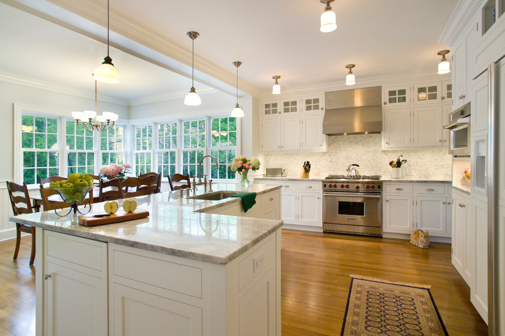 This is an example of a traditional u-shaped eat-in kitchen in New York with an undermount sink, shaker cabinets, white cabinets and panelled appliances.