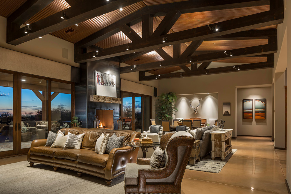 Photo of a large formal open concept living room in Phoenix with beige walls, concrete floors, a standard fireplace, a metal fireplace surround, a wall-mounted tv and brown floor.