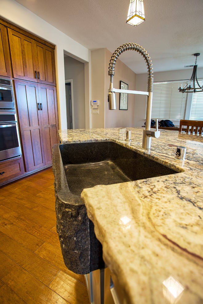 Open concept kitchen - large rustic dark wood floor and brown floor open concept kitchen idea in Sacramento with a farmhouse sink, shaker cabinets, brown cabinets, granite countertops, beige backsplash, subway tile backsplash, stainless steel appliances, an island and brown countertops