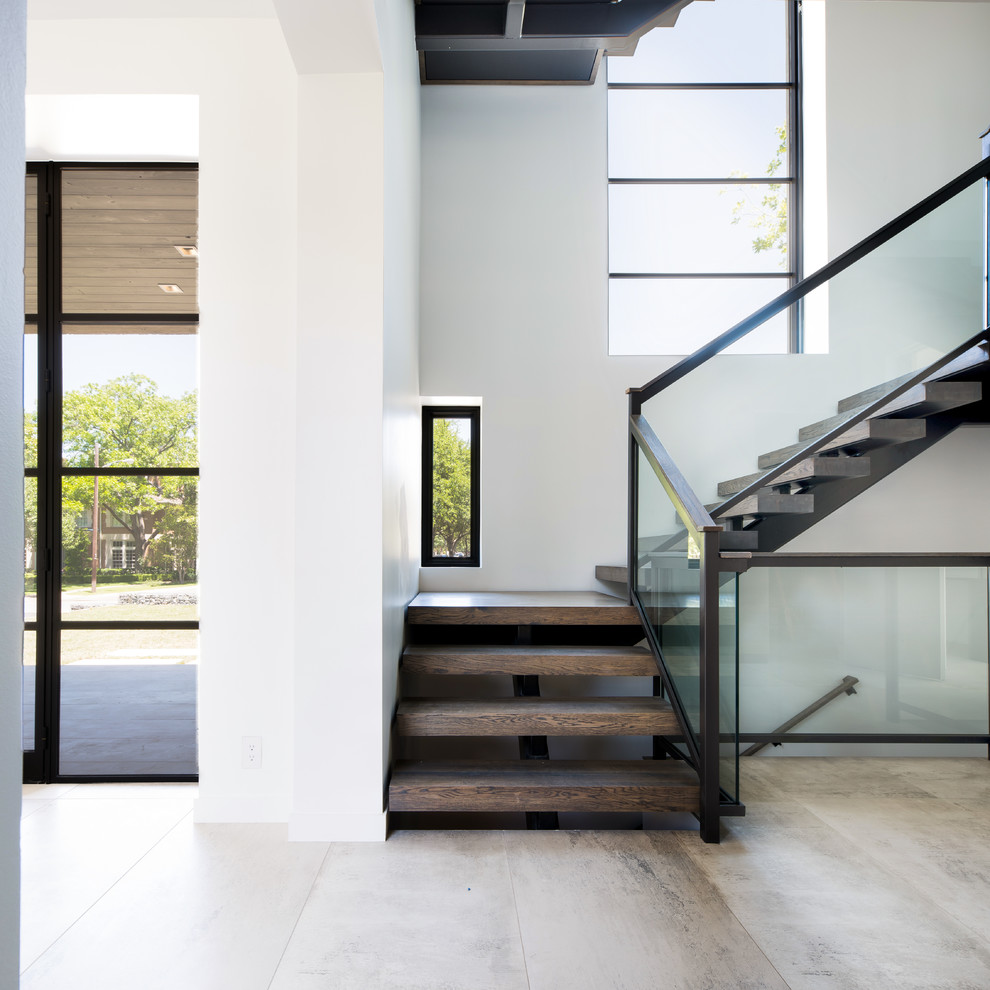 This is an example of a mid-sized modern wood l-shaped staircase in Dallas with open risers and glass railing.