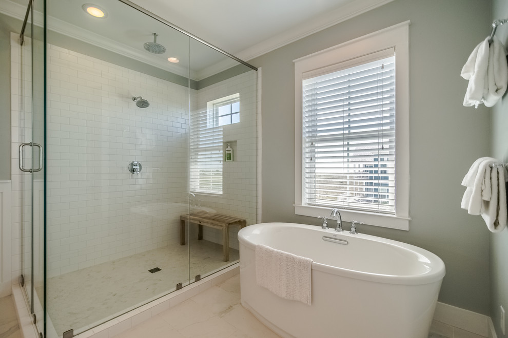 This is an example of a mid-sized beach style master bathroom in Houston with shaker cabinets, white cabinets, a freestanding tub, a corner shower, a one-piece toilet, white tile, subway tile, grey walls, porcelain floors, an undermount sink, engineered quartz benchtops, multi-coloured floor and a shower curtain.