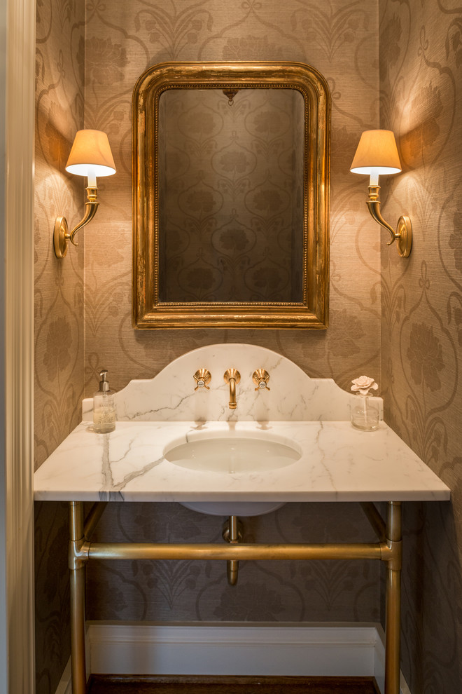 This is an example of a large traditional powder room in Philadelphia with an undermount sink, marble benchtops, beige walls and white benchtops.