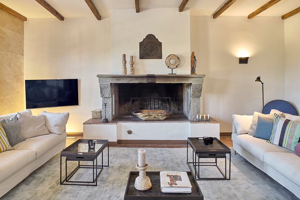 Inspiration for a mid-sized mediterranean family room in Florence with white walls, medium hardwood floors, a standard fireplace, a wall-mounted tv, brown floor and a stone fireplace surround.