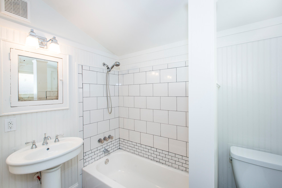 This is an example of a small arts and crafts 3/4 bathroom in Charlotte with an alcove tub, an alcove shower, a two-piece toilet, white tile, porcelain tile, beige walls, porcelain floors and a pedestal sink.