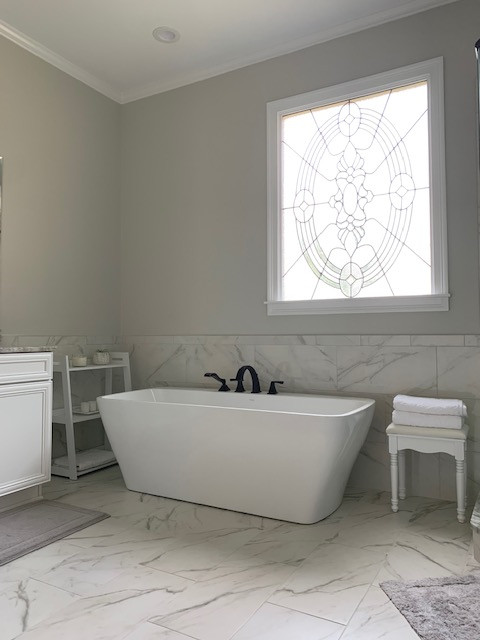 Mid-sized transitional master white tile porcelain tile, white floor and double-sink freestanding bathtub photo with recessed-panel cabinets, white cabinets, a two-piece toilet, gray walls, an undermount sink, granite countertops, a hinged shower door, beige countertops and a built-in vanity