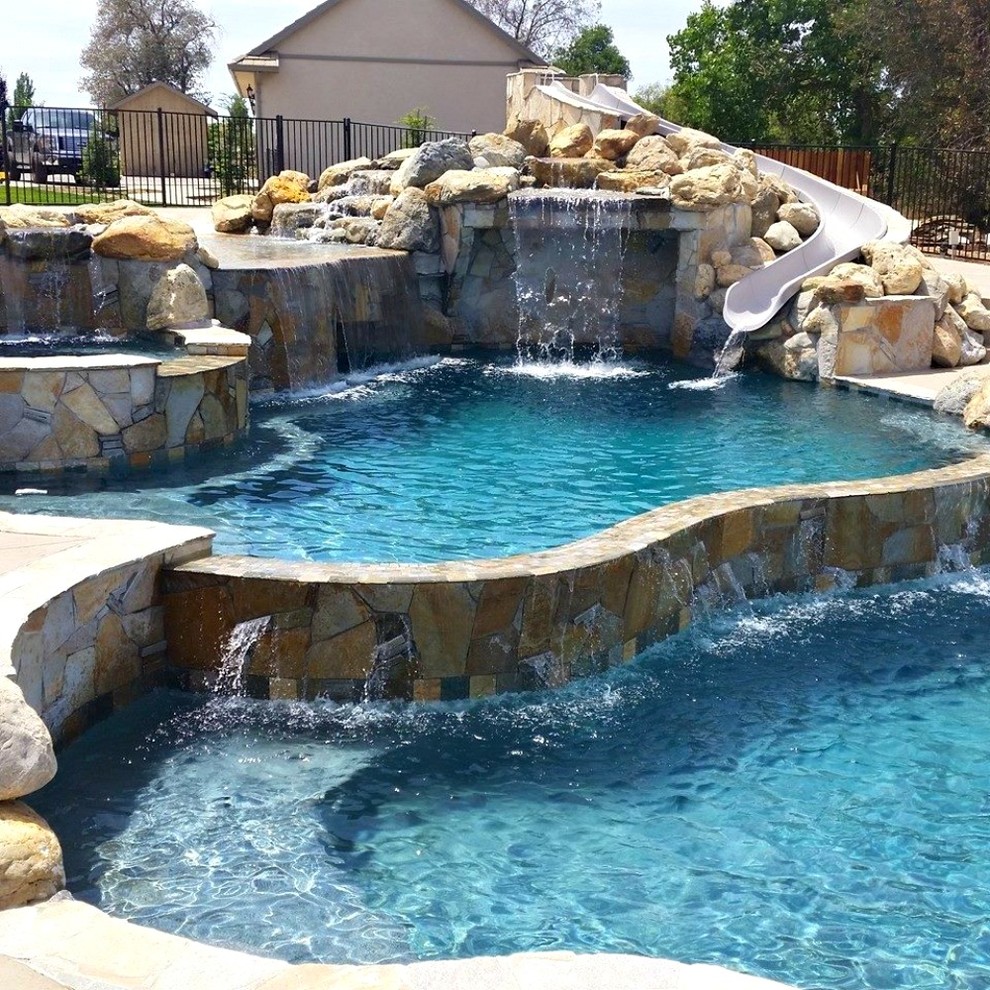 This is an example of a large country backyard custom-shaped natural pool in Sacramento with a water slide and concrete slab.