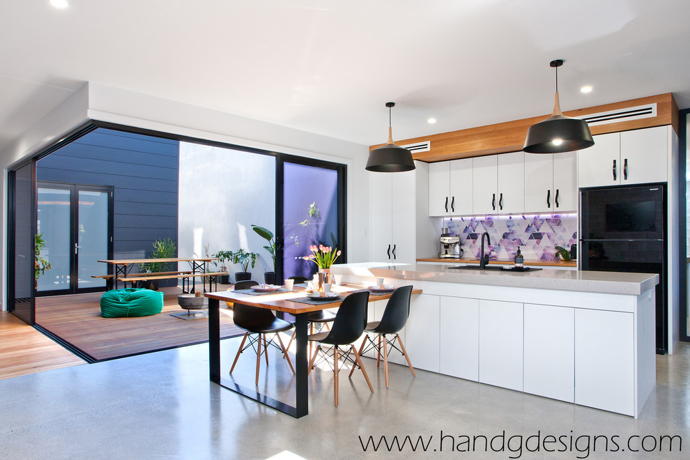 This is an example of a kitchen in Sunshine Coast with concrete benchtops, multi-coloured splashback, concrete floors and with island.