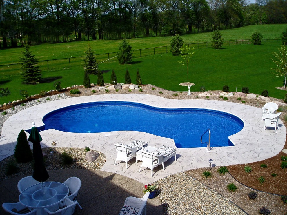 Example of a large backyard custom-shaped pool design in Grand Rapids