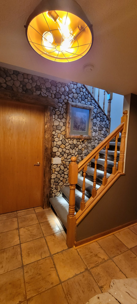 Example of a small mountain style walk-out terra-cotta tile and wall paneling basement design with a bar