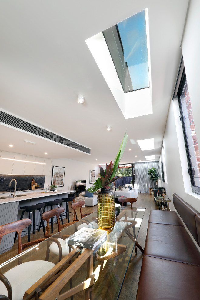 Design ideas for a contemporary open plan dining in Sydney with white walls, light hardwood floors and brown floor.