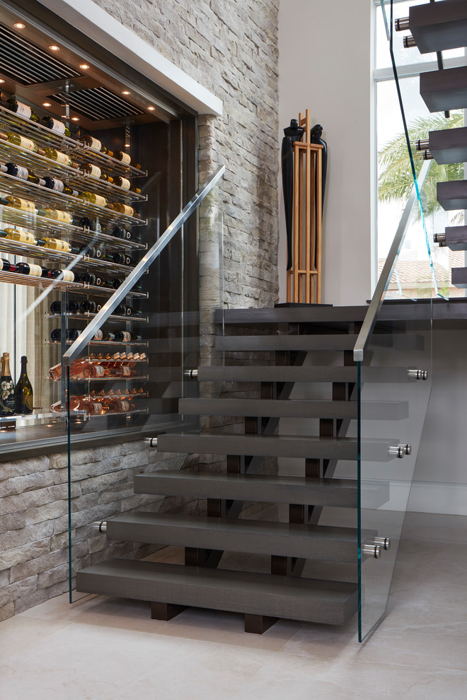 This is an example of a contemporary floating staircase in Miami with open risers and glass railing.