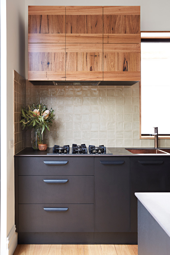 Photo of a small l-shaped eat-in kitchen in Melbourne with a double-bowl sink, black cabinets, quartz benchtops, green splashback, stainless steel appliances, with island and black benchtop.