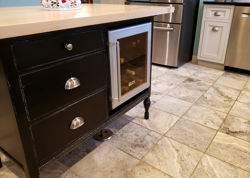 Example of a large transitional u-shaped ceramic tile and beige floor kitchen pantry design with a farmhouse sink, recessed-panel cabinets, white cabinets, quartz countertops, white backsplash, ceramic backsplash, stainless steel appliances, an island and black countertops