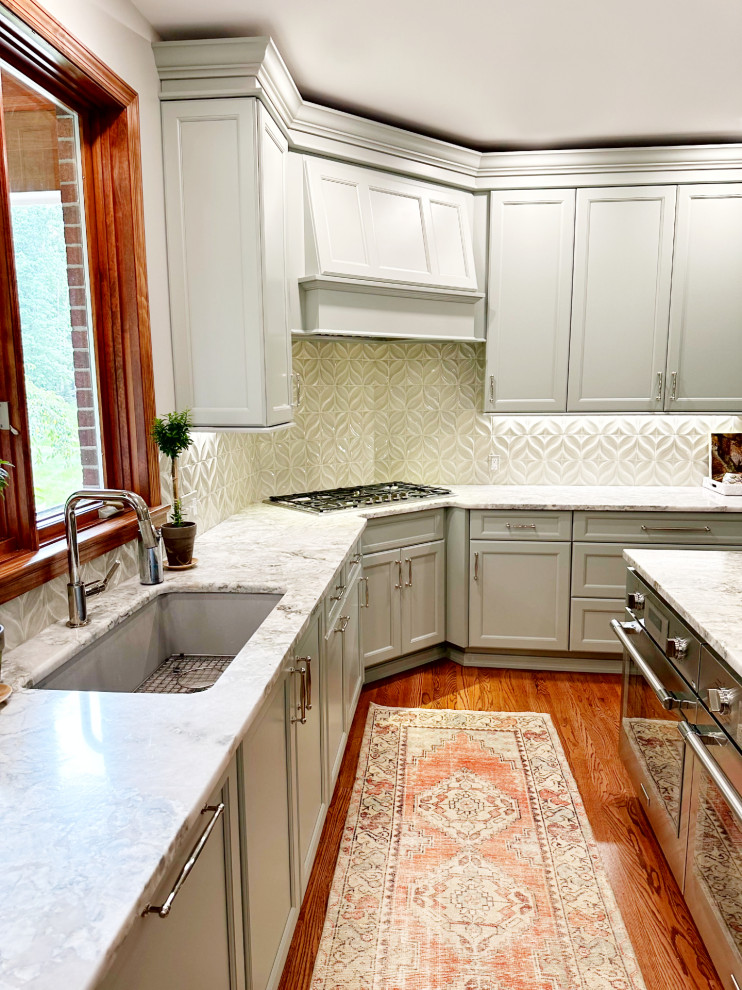 Inspiration for a transitional l-shaped medium tone wood floor eat-in kitchen remodel with shaker cabinets, green cabinets, quartzite countertops, porcelain backsplash, paneled appliances and an island
