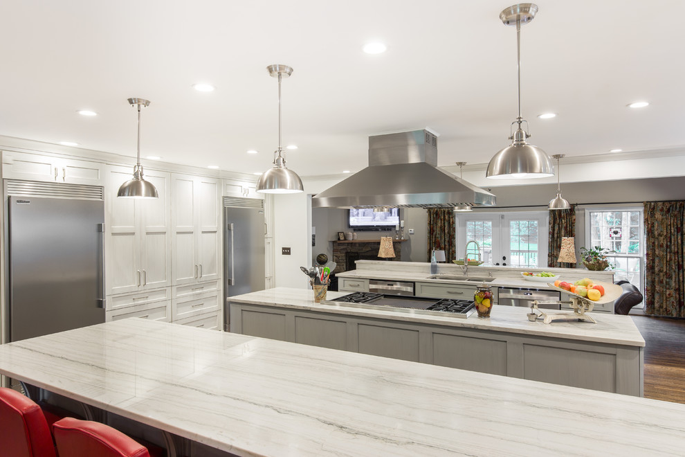 Large transitional single-wall medium tone wood floor and brown floor eat-in kitchen photo with an undermount sink, shaker cabinets, white cabinets, marble countertops, multicolored backsplash, matchstick tile backsplash, stainless steel appliances and two islands