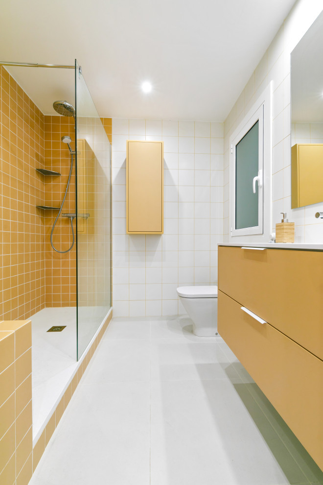 Inspiration pour une grande salle de bain principale minimaliste avec un placard à porte plane, des portes de placard jaunes, une douche ouverte, WC à poser, un carrelage jaune, des carreaux de céramique, un mur blanc, un sol en carrelage de céramique, un lavabo intégré, un plan de toilette en surface solide, un sol gris, un plan de toilette blanc, des toilettes cachées, meuble simple vasque et meuble-lavabo sur pied.