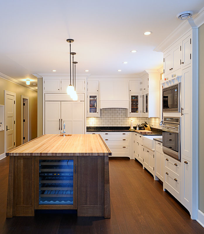 Inspiration for a large transitional l-shaped dark wood floor and brown floor enclosed kitchen remodel with a farmhouse sink, white backsplash, subway tile backsplash, paneled appliances, beaded inset cabinets, white cabinets, an island and black countertops