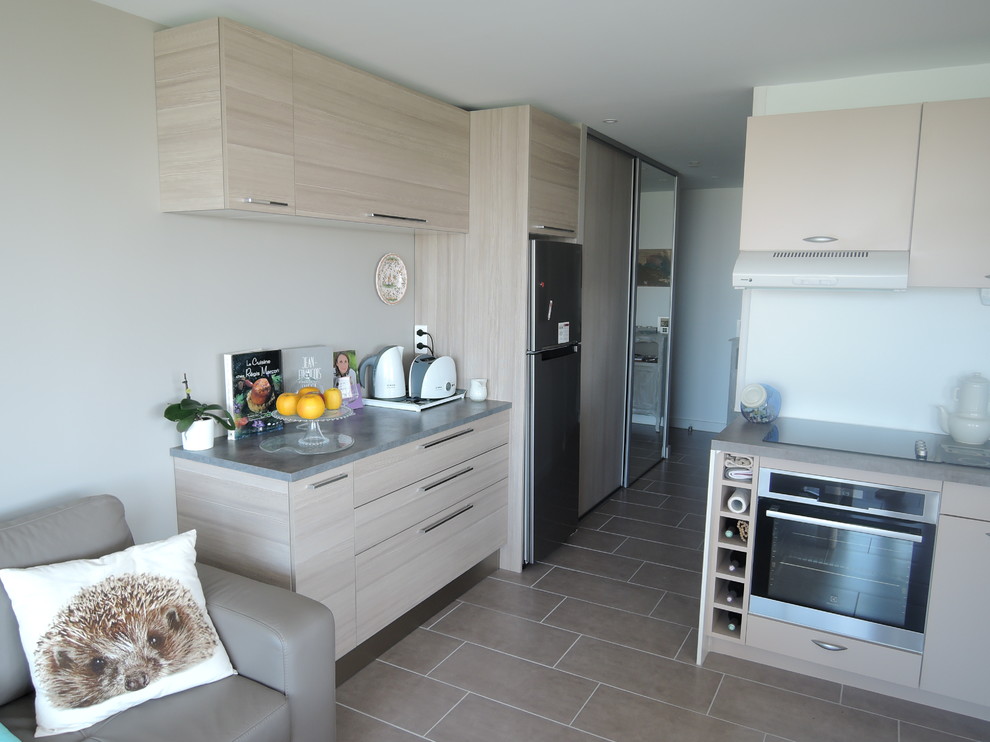 Mid-sized beach style u-shaped open plan kitchen in Montpellier with a single-bowl sink, light wood cabinets, laminate benchtops, grey splashback, stainless steel appliances, ceramic floors and no island.