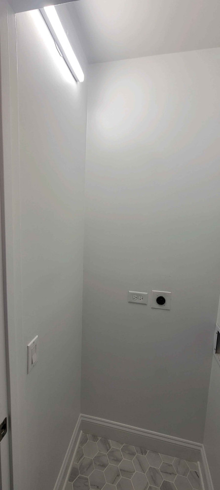 Diseño de cuarto de lavado contemporáneo pequeño con armarios con paneles lisos, puertas de armario blancas, paredes blancas, suelo de baldosas de porcelana y lavadora y secadora apiladas