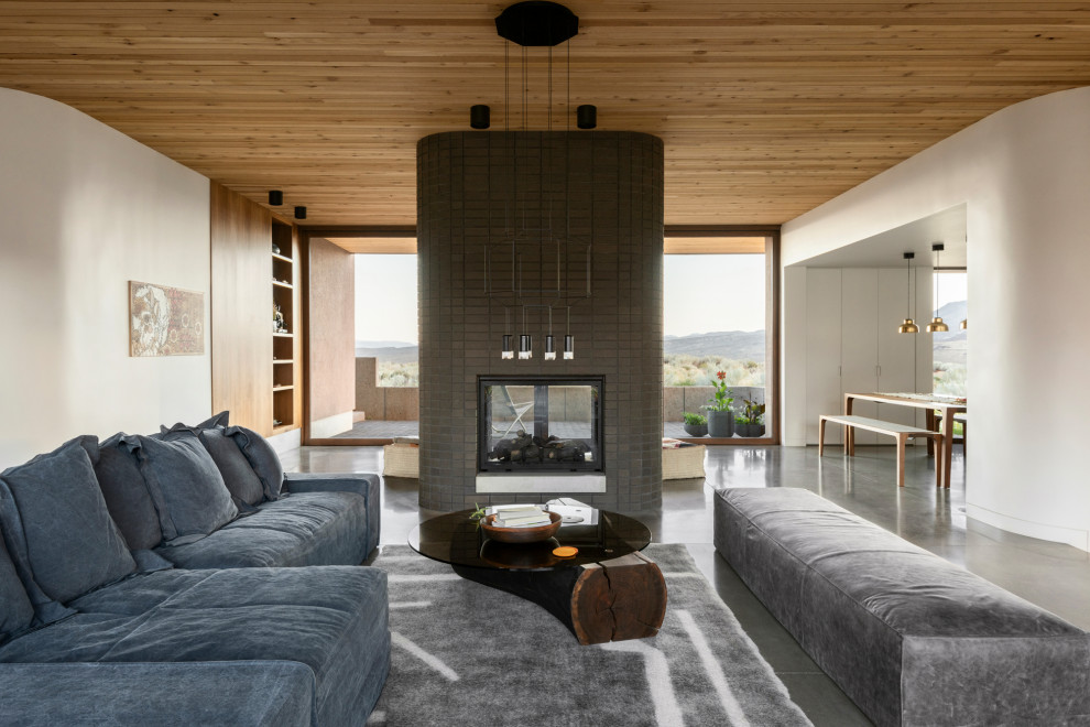 Aménagement d'un salon ouvert avec un mur blanc, sol en béton ciré, une cheminée double-face, un manteau de cheminée en brique, un sol gris et un plafond en bois.