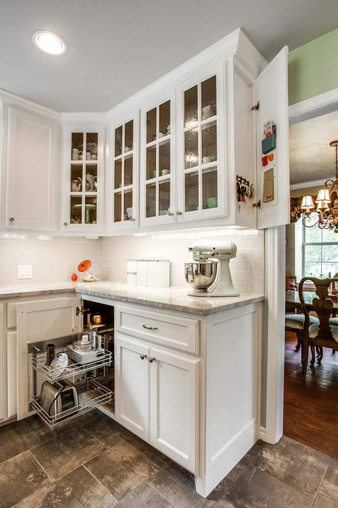 Photo of a mid-sized country u-shaped separate kitchen in Dallas with a farmhouse sink, recessed-panel cabinets, white cabinets, quartzite benchtops, white splashback, subway tile splashback, stainless steel appliances, porcelain floors, with island and grey floor.