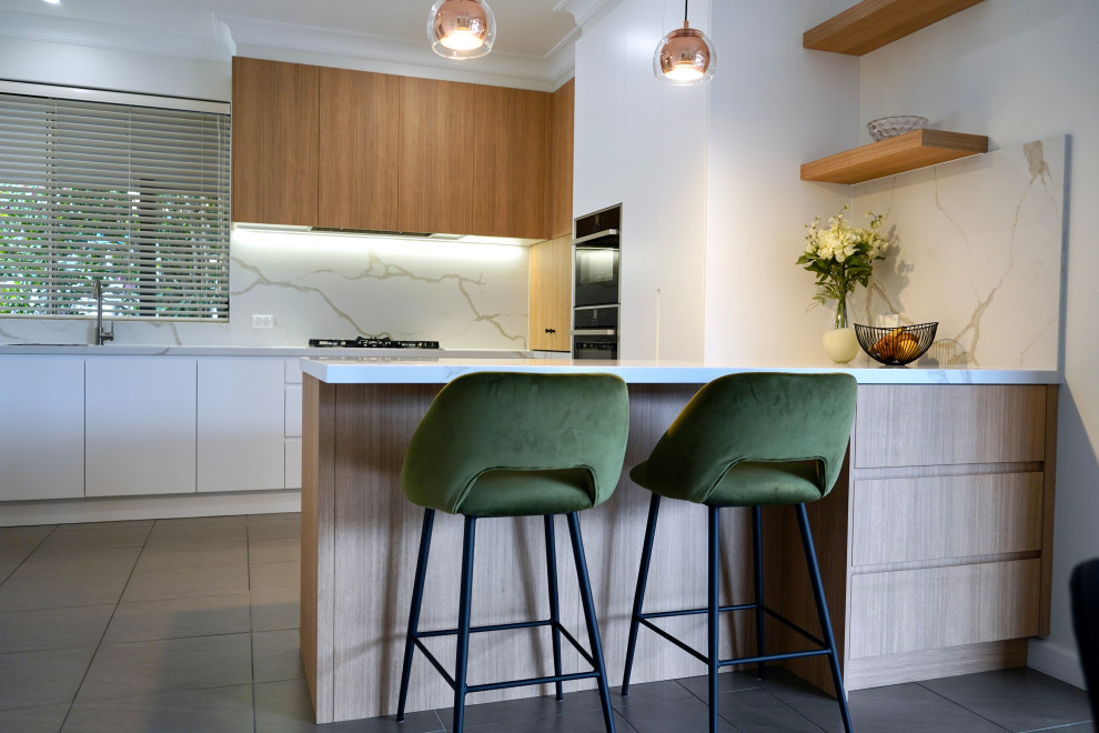 Inspiration for a mid-sized l-shaped open plan kitchen in Sydney with an undermount sink, flat-panel cabinets, brown cabinets, quartz benchtops, white splashback, engineered quartz splashback, stainless steel appliances, ceramic floors, with island, grey floor and white benchtop.