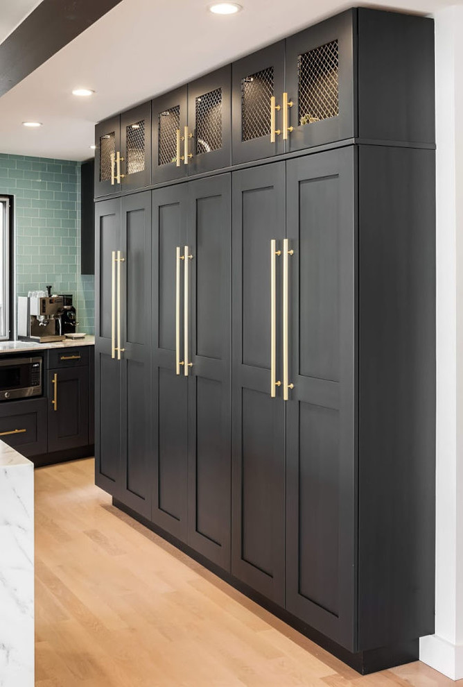 Inspiration for a large contemporary u-shaped eat-in kitchen in Seattle with an undermount sink, recessed-panel cabinets, black cabinets, marble benchtops, green splashback, glass tile splashback, stainless steel appliances, light hardwood floors, with island, brown floor and white benchtop.