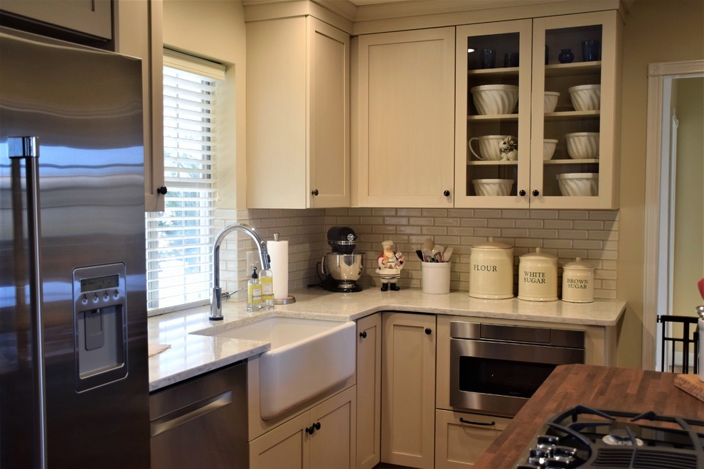 Inspiration for a mid-sized transitional u-shaped brick floor eat-in kitchen remodel with a farmhouse sink, shaker cabinets, white cabinets, quartzite countertops, white backsplash, subway tile backsplash, stainless steel appliances and an island