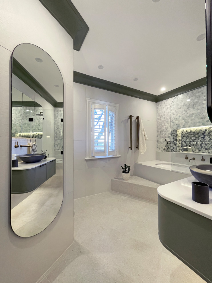 На фото: большая главная ванная комната в современном стиле с фасадами в стиле шейкер, зелеными фасадами, полновстраиваемой ванной, душем над ванной, инсталляцией, белой плиткой, керамогранитной плиткой, разноцветными стенами, полом из керамогранита, настольной раковиной, столешницей из искусственного кварца, бежевым полом, душем с распашными дверями, белой столешницей, нишей, тумбой под одну раковину и напольной тумбой с
