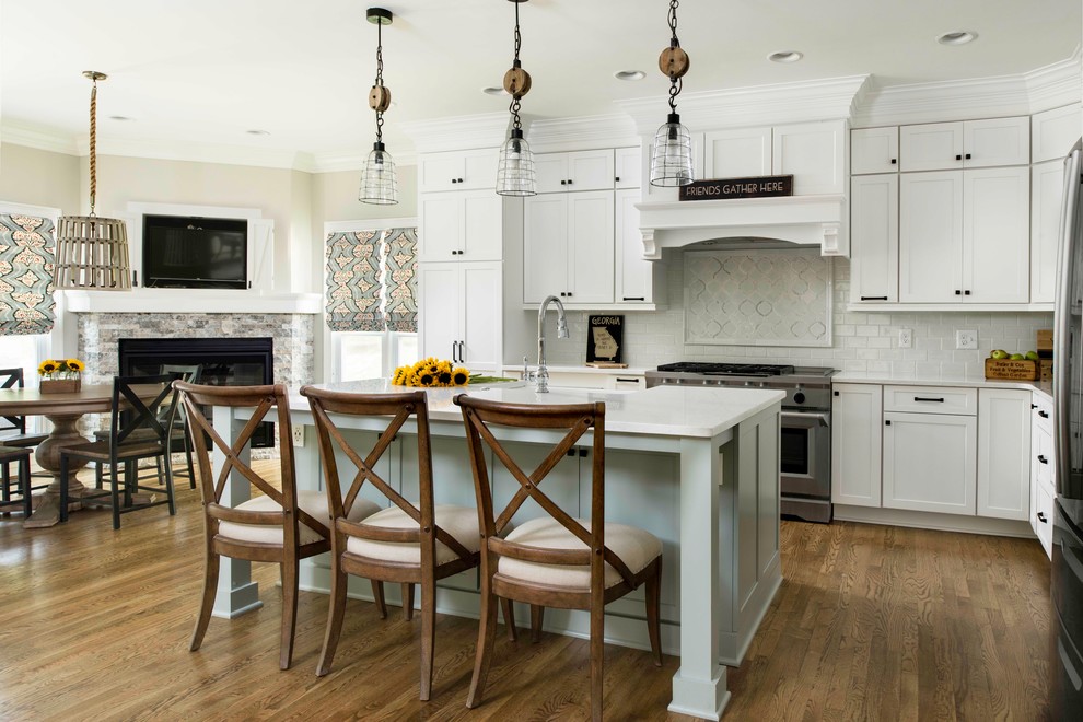 Photo of a large country l-shaped kitchen in Atlanta with shaker cabinets, white cabinets, quartz benchtops, white splashback, stainless steel appliances, with island, dark hardwood floors and brown floor.