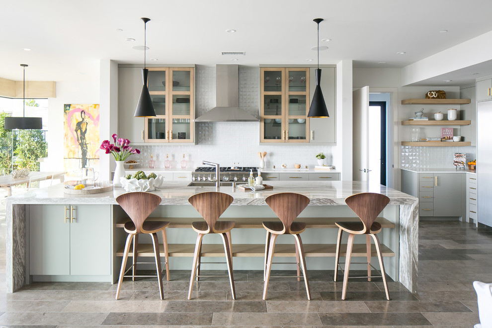 This is an example of a contemporary l-shaped open plan kitchen in Orange County with flat-panel cabinets, green cabinets, white splashback, stainless steel appliances and with island.