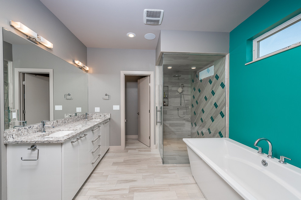 This is an example of a large modern master bathroom in Other with flat-panel cabinets, white cabinets, granite benchtops, a freestanding tub, a curbless shower, beige tile, ceramic tile, grey walls, ceramic floors, a two-piece toilet and an undermount sink.