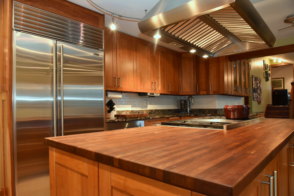 Kitchen - mid-sized single-wall porcelain tile kitchen idea with an undermount sink, beaded inset cabinets, granite countertops, white backsplash, subway tile backsplash, stainless steel appliances and an island