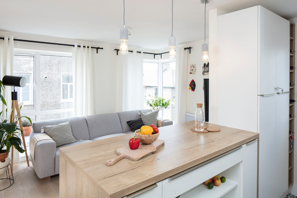 This is an example of a mid-sized scandinavian galley open plan kitchen in Dublin with flat-panel cabinets, white cabinets, laminate benchtops, multi-coloured splashback, porcelain splashback, panelled appliances, porcelain floors, a peninsula and beige floor.