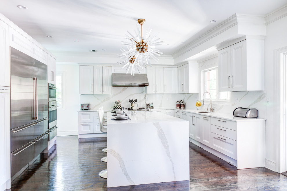 Large transitional galley dark wood floor and brown floor open concept kitchen photo in New York with a drop-in sink, shaker cabinets, white cabinets, quartzite countertops, white backsplash, stone slab backsplash, stainless steel appliances and an island