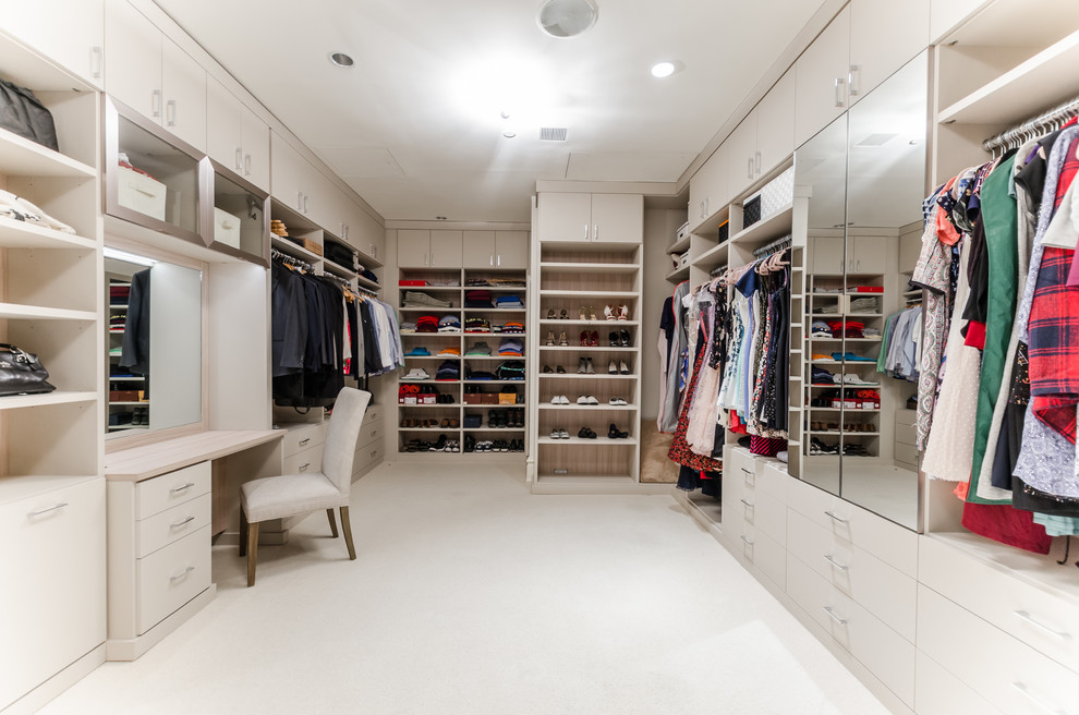 This is an example of a contemporary gender-neutral dressing room in New York with open cabinets, carpet, white cabinets and white floor.