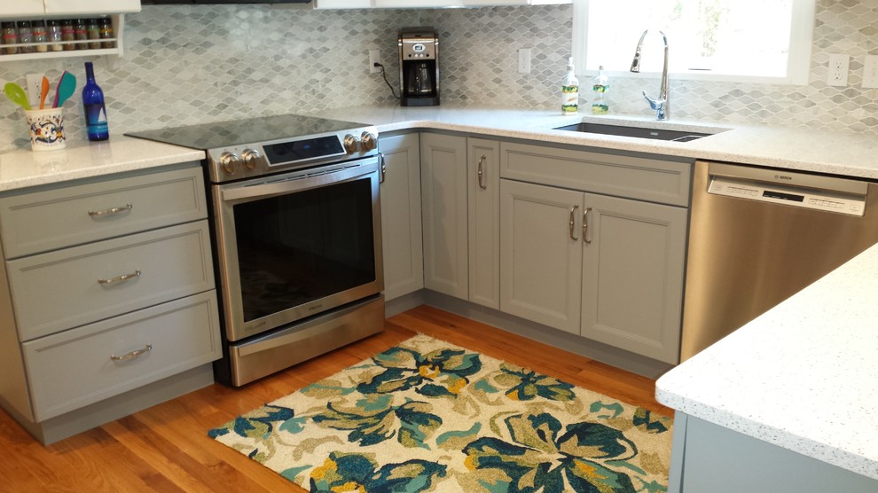 Example of a transitional u-shaped medium tone wood floor kitchen design in Boston with an undermount sink, gray cabinets, quartz countertops, multicolored backsplash, stainless steel appliances and a peninsula