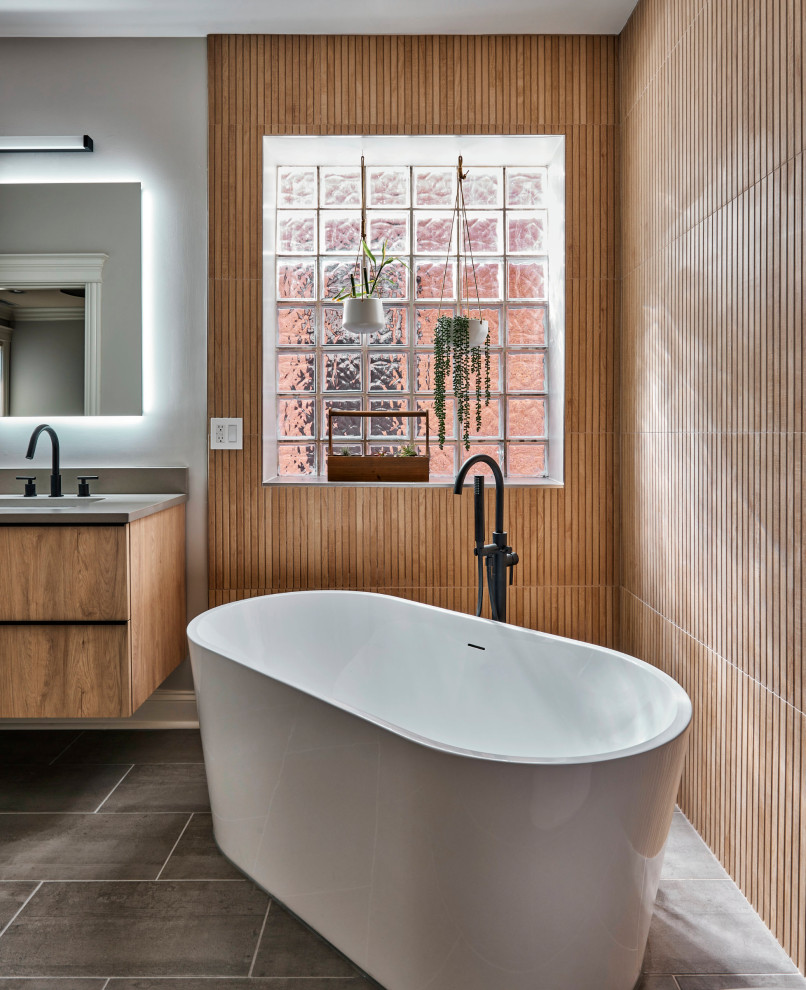 Medium sized contemporary ensuite bathroom in Chicago with flat-panel cabinets, brown cabinets, a freestanding bath, brown tiles, wood-effect tiles, concrete flooring, a submerged sink, quartz worktops, grey floors, double sinks, a floating vanity unit, wood walls, grey walls and grey worktops.