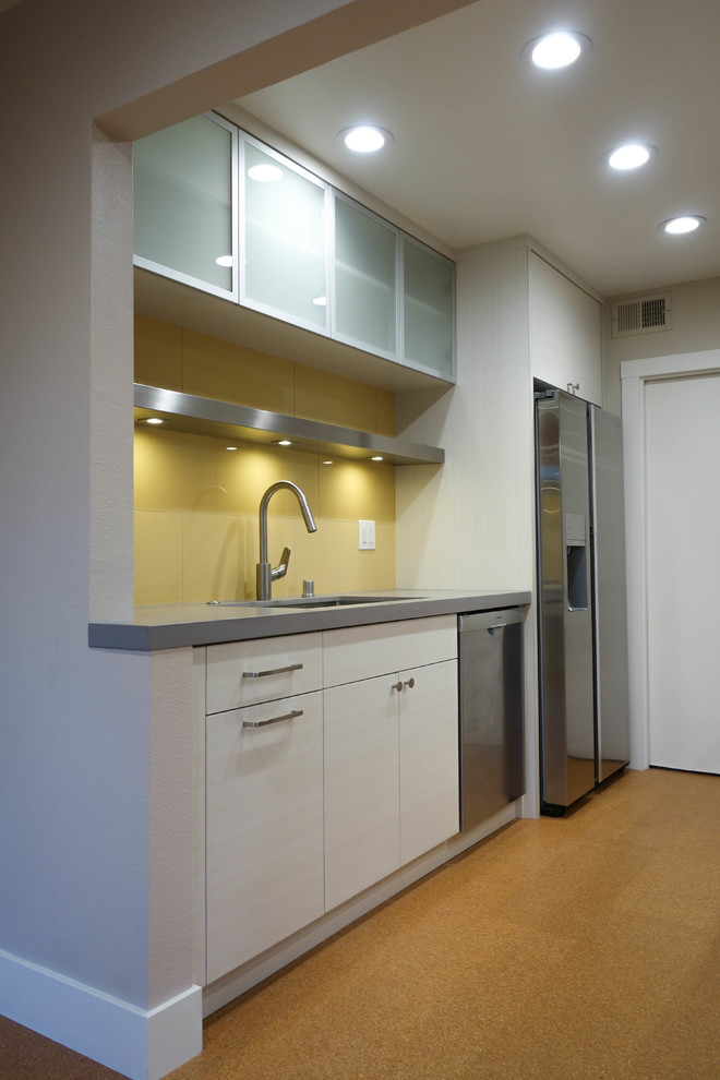 Photo of a small contemporary galley eat-in kitchen in San Francisco with a single-bowl sink, flat-panel cabinets, beige cabinets, quartz benchtops, yellow splashback, porcelain splashback, stainless steel appliances, cork floors, yellow floor and grey benchtop.