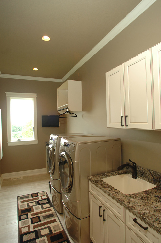 This is an example of a mid-sized traditional single-wall dedicated laundry room in Other with an undermount sink, recessed-panel cabinets, granite benchtops, brown walls, porcelain floors, a side-by-side washer and dryer and white cabinets.