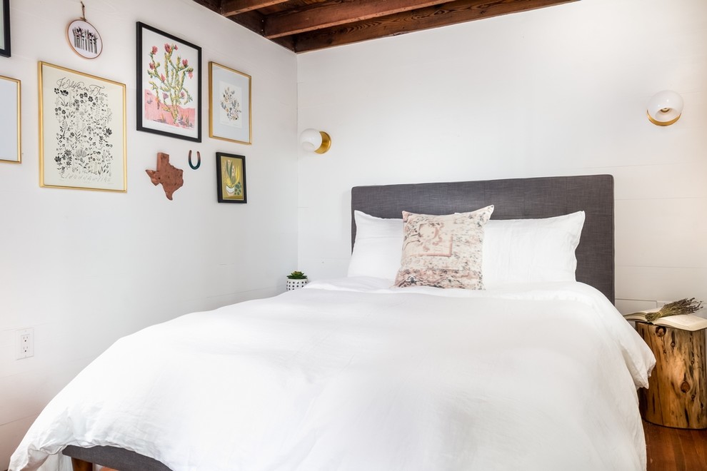 Example of a cottage medium tone wood floor bedroom design in Austin with white walls and no fireplace