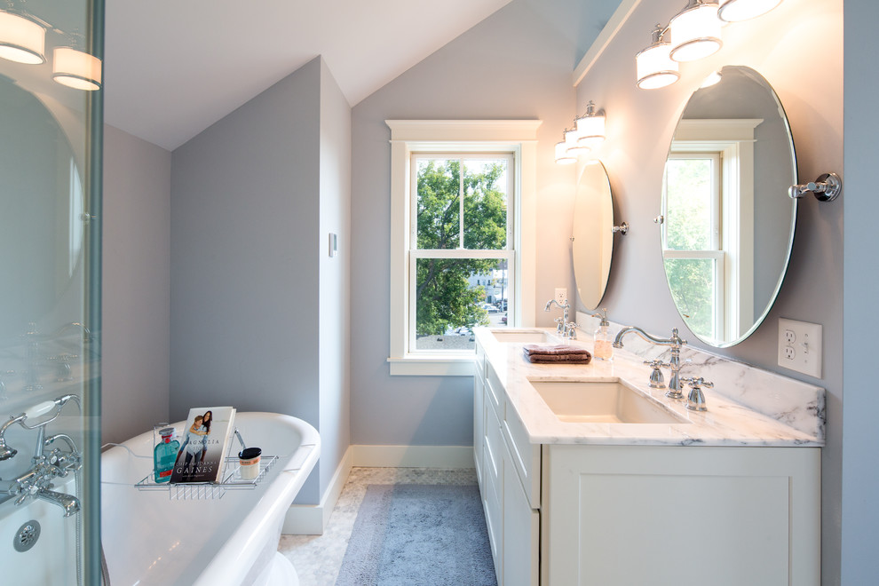 This is an example of a transitional master bathroom in Minneapolis with white cabinets, a freestanding tub, a curbless shower, grey walls, marble floors, an undermount sink, marble benchtops, white floor and shaker cabinets.